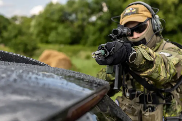 airsoft player aiming airsoft gun over the car roof